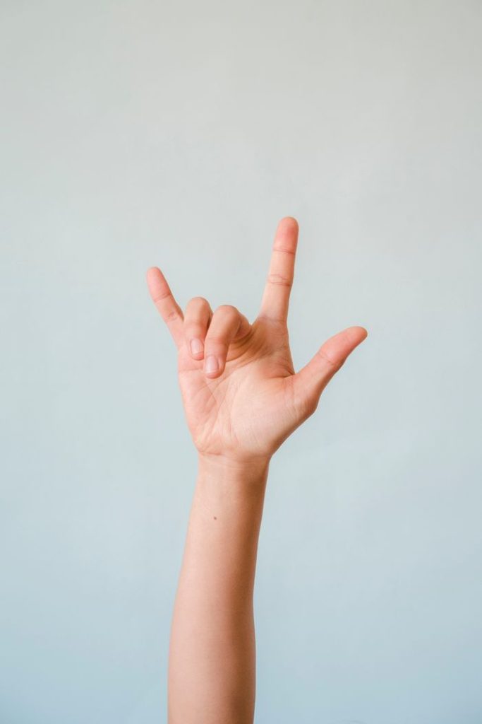 Close-up of I Love You hand gesture in American Sign Language against a white background.