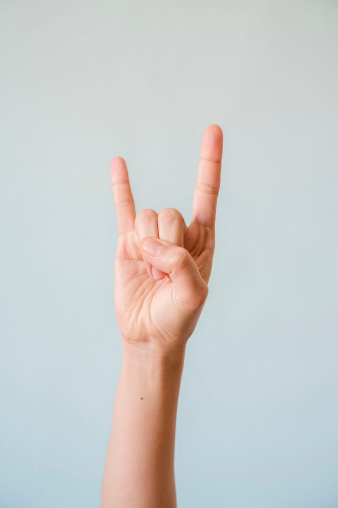 Hand showing rock and roll gesture against a white background, perfect for music themes.