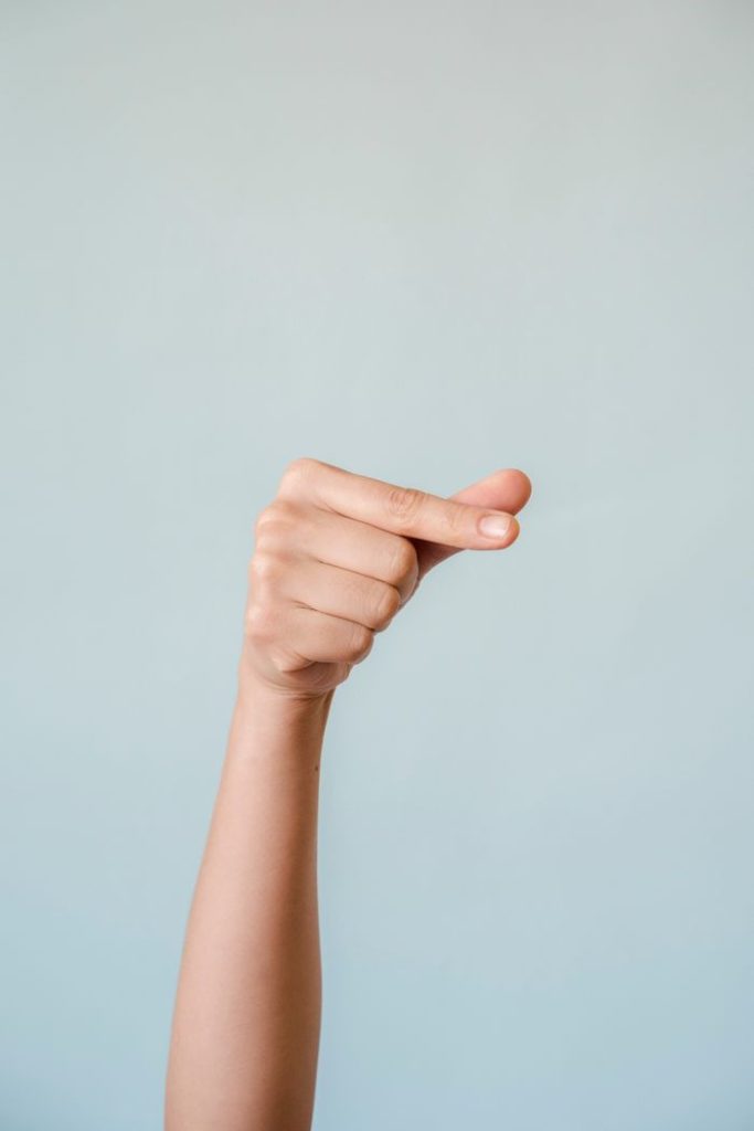 A womans hand making a gesture against a calm blue background, symbolizing communication.